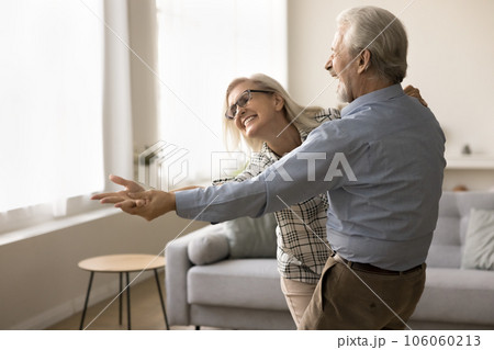 Joyful older retired husband and wife dancing to music 106060213