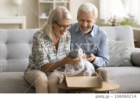 Cheerful senior online store customers couple opening parcel from webstore Cheerful senior online store customers couple opening parcel from webstore 106060214