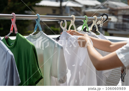 洗濯物をベランダで干している若い女性 106060989