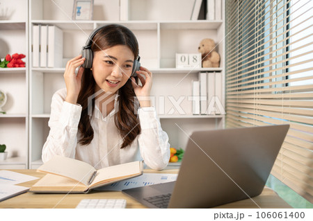 Beautiful young asian woman watching live video or video call of teacher teaching on laptop in her home, Take notes of important conversations and messages during the teacher's teaching. Beautiful young asian woman watching live video or video call of teacher teaching on laptop in her home, Take notes of important conversations and messages during the teacher's teaching. 106061400