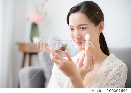 ブラシで化粧のチークで仕上げをする美しい女性の写真やや俯瞰 ブラシで化粧のチークで仕上げをする美しい女性の写真やや俯瞰 106061642