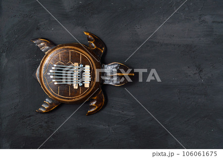 Kalimba turtle on a black background. Traditional musical instrument. Folk music or meditative music concept. Copy space 106061675
