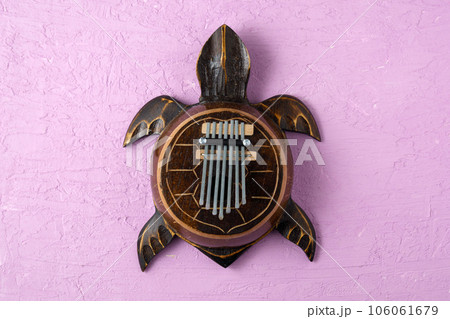 Kalimba turtle on a purple background. Traditional musical instrument. Folk music or meditative music concept Kalimba turtle on a purple background. Traditional musical instrument. Folk music or meditative music concept 106061679