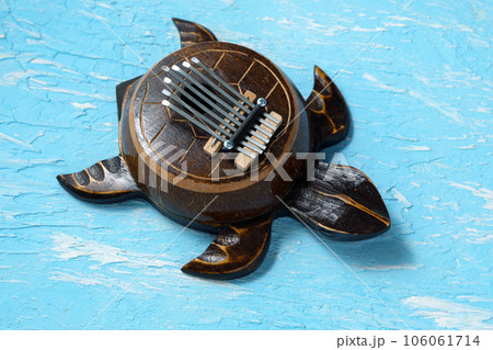 Kalimba turtle on a blue background. Traditional musical instrument. Folk music or meditative music concept Kalimba turtle on a blue background. Traditional musical instrument. Folk music or meditative music concept 106061714