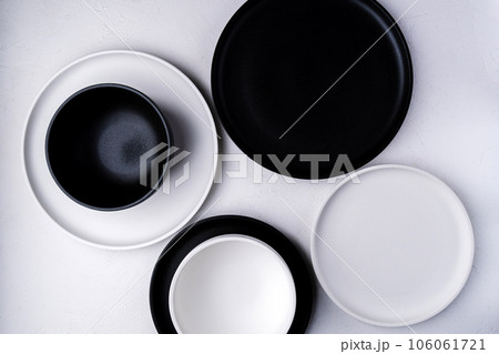 Empty ceramic plate, black and white on a concrete white background. Stylish tableware 106061721