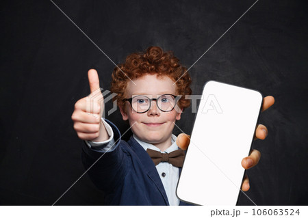 Happy child schoolboy showing smartphone with blank empty white screen display  Happy child schoolboy showing smartphone with blank empty white screen display  106063524