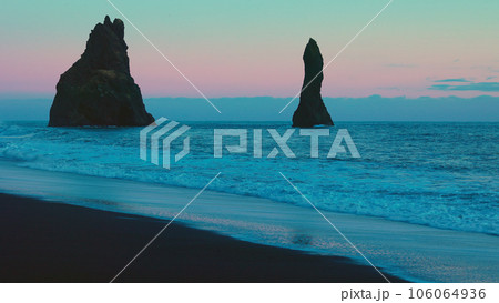 Atlantic shore with majestic rocks on reynisfjara beach and reynisfjall mountain, nordic black sand beaches. Icelandic coastline scenery with ocean waves, pink sky. Handheld shot. Atlantic shore with majestic rocks on reynisfjara beach and reynisfjall mountain, nordic black sand beaches. Icelandic coastline scenery with ocean waves, pink sky. Handheld shot. 106064936
