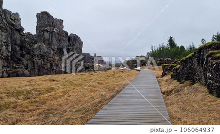 Rocky mountain range in arctic scenery, thingvellir national park with spectacular landscapes and massive cliffs in iceland. Rock formations creating hills in icelandic valley with walkway. Rocky mountain range in arctic scenery, thingvellir national park with spectacular landscapes and massive cliffs in iceland. Rock formations creating hills in icelandic valley with walkway. 106064937