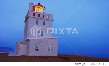 Dyrholaey lighthouse on arctic coastline, beautiful old building with navigation light on shore. Tower structure used for guidance on icelandic cliff, vik city landscapes. Handheld shot. Dyrholaey lighthouse on arctic coastline, beautiful old building with navigation light on shore. Tower structure used for guidance on icelandic cliff, vik city landscapes. Handheld shot. 106064949