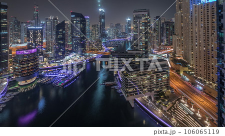 Aerial view to Dubai marina skyscrapers around canal with floating boats night timelapse Aerial view to Dubai marina skyscrapers around canal with floating boats night timelapse 106065119