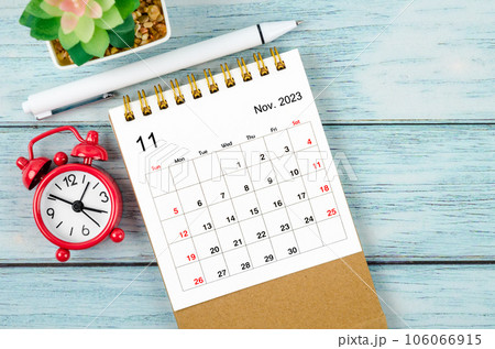 The November 2023 Monthly desk calendar for the organizer to plan 2023 year with alarm clock and pen on wooden table. The November 2023 Monthly desk calendar for the organizer to plan 2023 year with alarm clock and pen on wooden table. 106066915