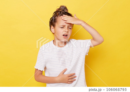 Unhealthy little girl with wet hair wearing casual white T-shirt standing isolated over yellow background groimacing from pain feeling terrible headache Unhealthy little girl with wet hair wearing casual white T-shirt standing isolated over yellow background groimacing from pain feeling terrible headache 106068793