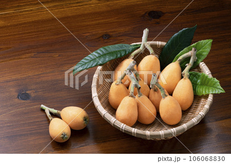 ざるに入れて葉を添えたびわ 106068830