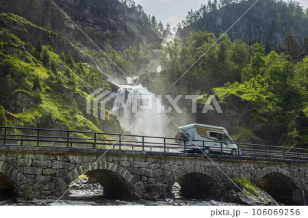 Holiday trip in motorhome, Caravan car Vacation. RV traveling on the road Latefossen Waterfall Odda Norway. Latefoss is a powerful, twin waterfall. 106069256