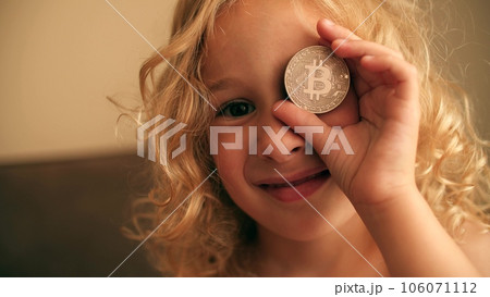 Little girl plays with a BTC bitcoin token or coin Little girl plays with a BTC bitcoin token or coin 106071112