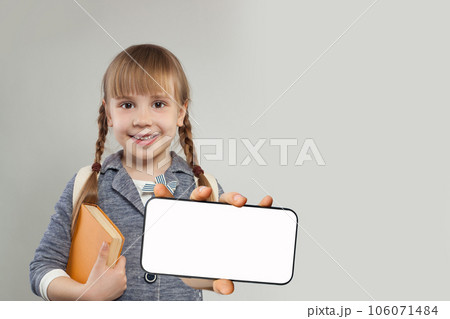 Pretty smiling child school student with blank empty white screen display on smartphone.  106071484