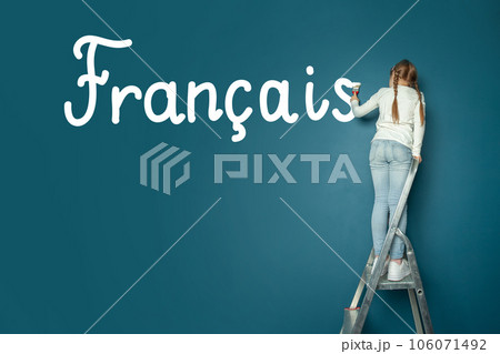 Child student girl standing on ladder and writing French language on blue chalkboard 106071492