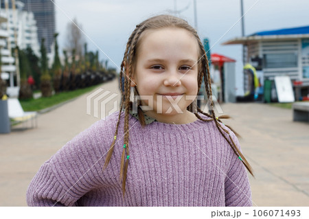Cheerful kid girl with pigtails smiling, outdoor portrait 106071493
