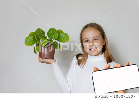 Happy smiling child holding green plant and showing smartphone Happy smiling child holding green plant and showing smartphone 106071507