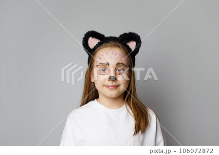Cheerful young child girl painting kitten face smiling on white studio background Cheerful young child girl painting kitten face smiling on white studio background 106072872