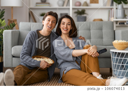 couple with popcorn sitting on sofa 106074013