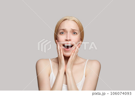 Portrait of happy surprised woman touching her face with hands isolated on grey background.  106074093