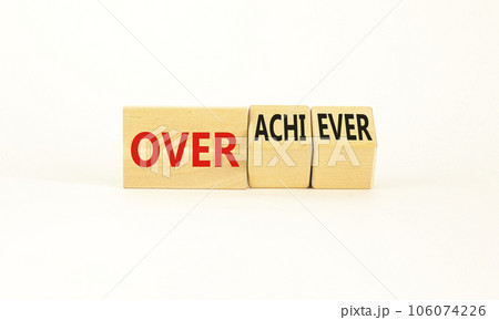 Achiever or overachiever symbol. Businessman turns wooden cubes and changes word Achiever to Overachiever. Beautiful white background. Business achiever or overachiever concept. Copy space. 106074226