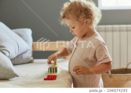 Creative learning game. Colorful sorting shapes. Creative art exploration. Cognitive skill development. Little blonde baby girl palying with wooden sorter toys at home interior Creative learning game. Colorful sorting shapes. Creative art exploration. Cognitive skill development. Little blonde baby girl palying with wooden sorter toys at home interior 106074295