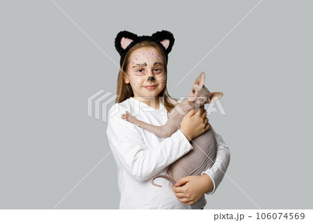 Young girl child painting kitten face holding cat pet on grey background 106074569