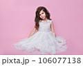 Beautiful little kid girl in white dress sitting on pink background. Happy birthday 106077138