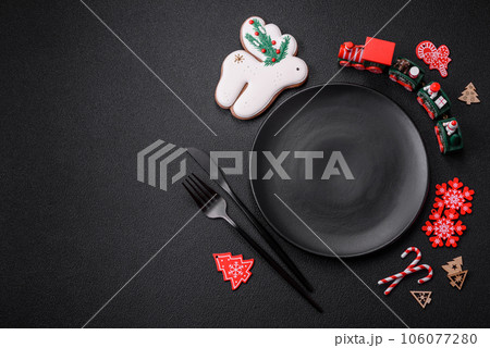 Empty dark ceramic plate with elements of Christmas decorations Empty dark ceramic plate with elements of Christmas decorations 106077280