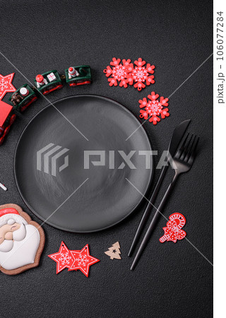 Empty dark ceramic plate with elements of Christmas decorations Empty dark ceramic plate with elements of Christmas decorations 106077284