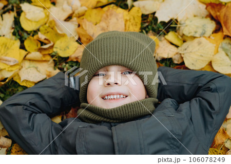 cute little boy laying on ground covered with yellow fallen leaves 106078249