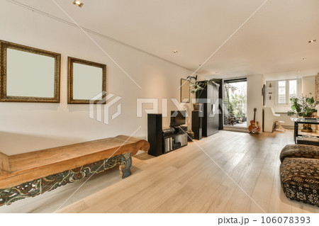 a living room with wood flooring and white walls in the center of the room is a large mirror on the wall 106078393