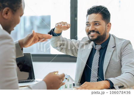 Real estate agent with House model is talking to clients about buying home insurance 106078436