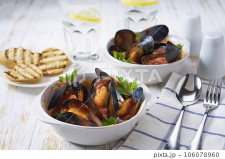 Traditional tomato soup with mussels with and toasted baguette on a white table. Traditional tomato soup with mussels with and toasted baguette on a white table. 106078960