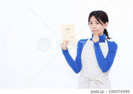 白い背景の前で給料袋を持ち悩んでいる30代の主婦 106078996