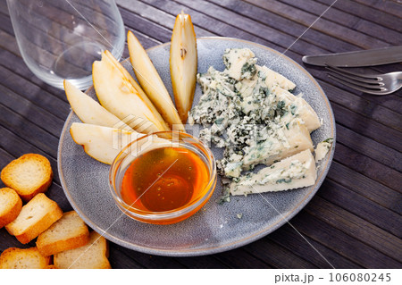 Roncari blue cheese served on plate with pear, croutons and honey 106080245