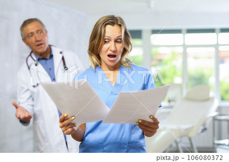 Elderly man doctor scolding adult female medic 106080372
