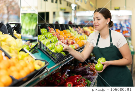Female seller in apron chooses juicy apple 106080391