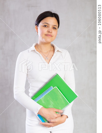 Student girl with several notebooks for writing poses in studio. 106080513