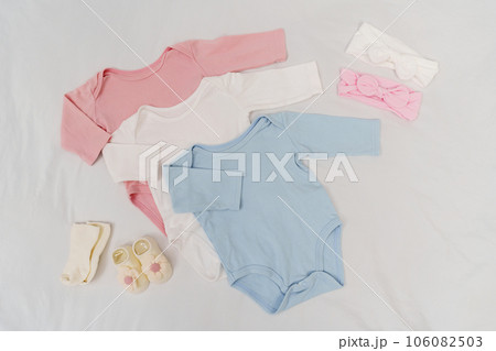 set of baby clothes and accessories on a white bed 106082503