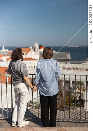 Back view of romantic hipster couple in love holding hands while walking on old city street 106082538