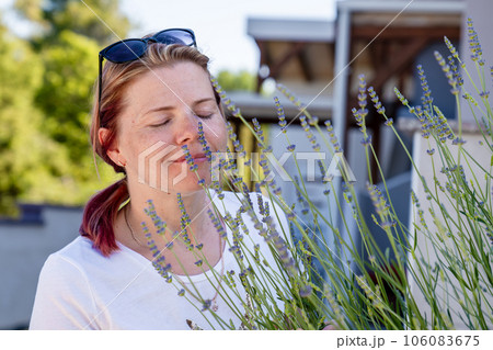 Aromatherapy, cute young womanenjoys the smell of lavender flowers while walking outdoor 106083675