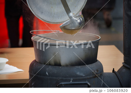 Outdoor preparing soup in a cast iron boiler 106083920
