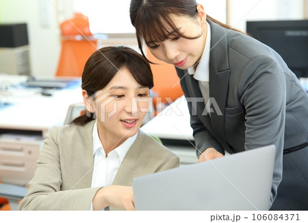 先輩からアドバイスをもらう新人女性会社員のイメージ 106084371
