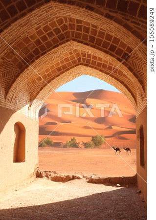 Ancient arch at the entrance to desert. View of sand dunes through stone arch. Travel, resort, vacation and holiday concept. Beautiful desert landscape with sand dunes and camel 106089249