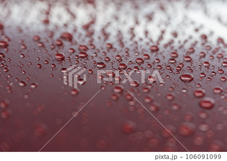 Rain droplets on red sports car surface with hydrophobic treatment Rain droplets on red sports car surface with hydrophobic treatment 106091099