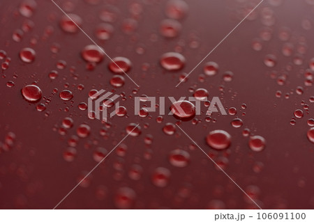 Rain droplets on red sports car surface with hydrophobic treatment 106091100
