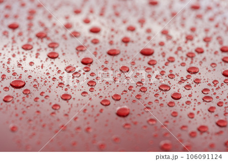 Rain droplets on red sports car surface with hydrophobic treatment 106091124